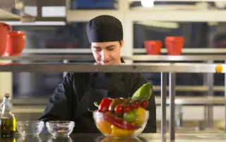 Chef cortando legumes em uma cozinha industrial moderna.