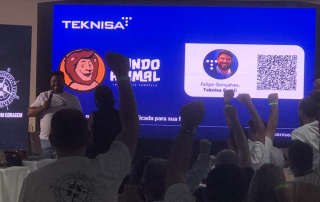 Imagem de um evento corporativo com o logotipo da Teknisa e do Mundo Animal projetados em um telão. Pessoas levantam os braços em interação com o momento. No canto superior direito, aparece o título: "Blog Teknisa - 3ª Convenção de Franqueados Mundo Animal", em fundo azul.